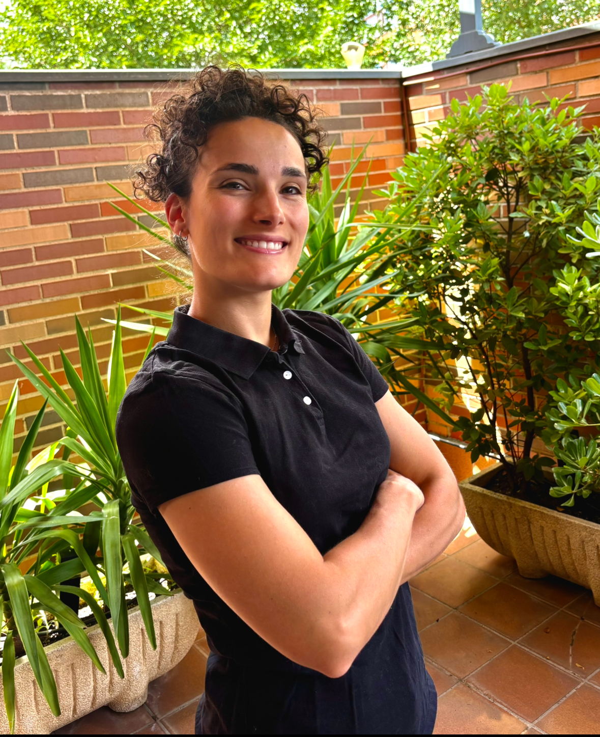 Carla, fisioterapeuta colegiada de Fisio Abuelos en Acción, sonriendo en el exterior de una vivienda en Madrid